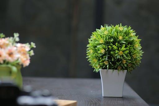 Aesthetic indoor plant arrangement featuring artificial greenery in a modern pot on a wooden table.